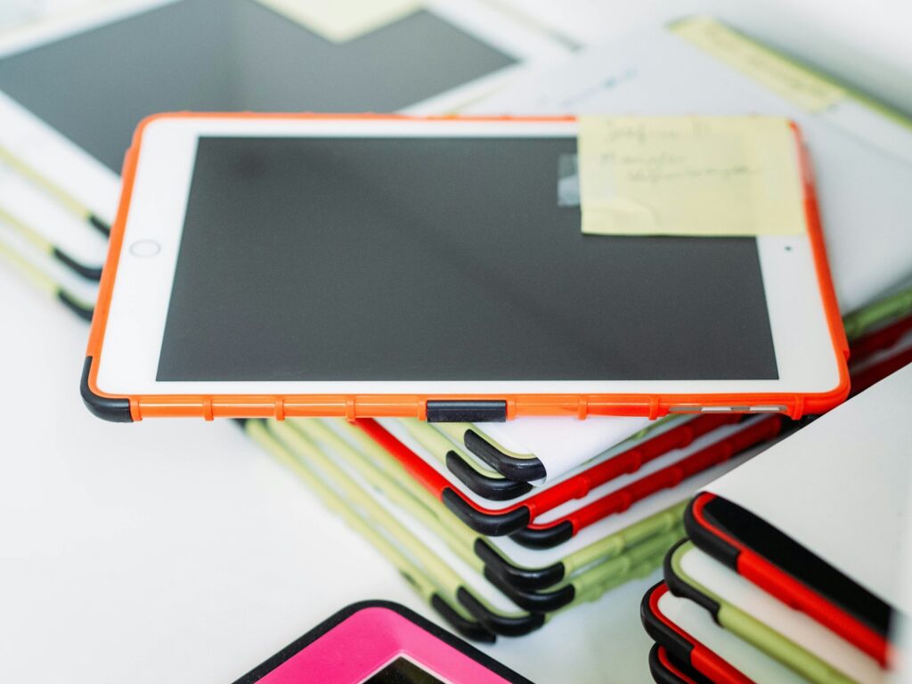 Stack of iPads in colorful protective cases prepared for classroom use by teachers and students